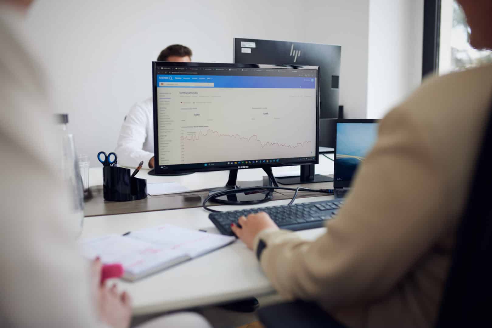 Person arbeitet am Computer mit Diagramm auf dem Bildschirm in einem modernen Büro.